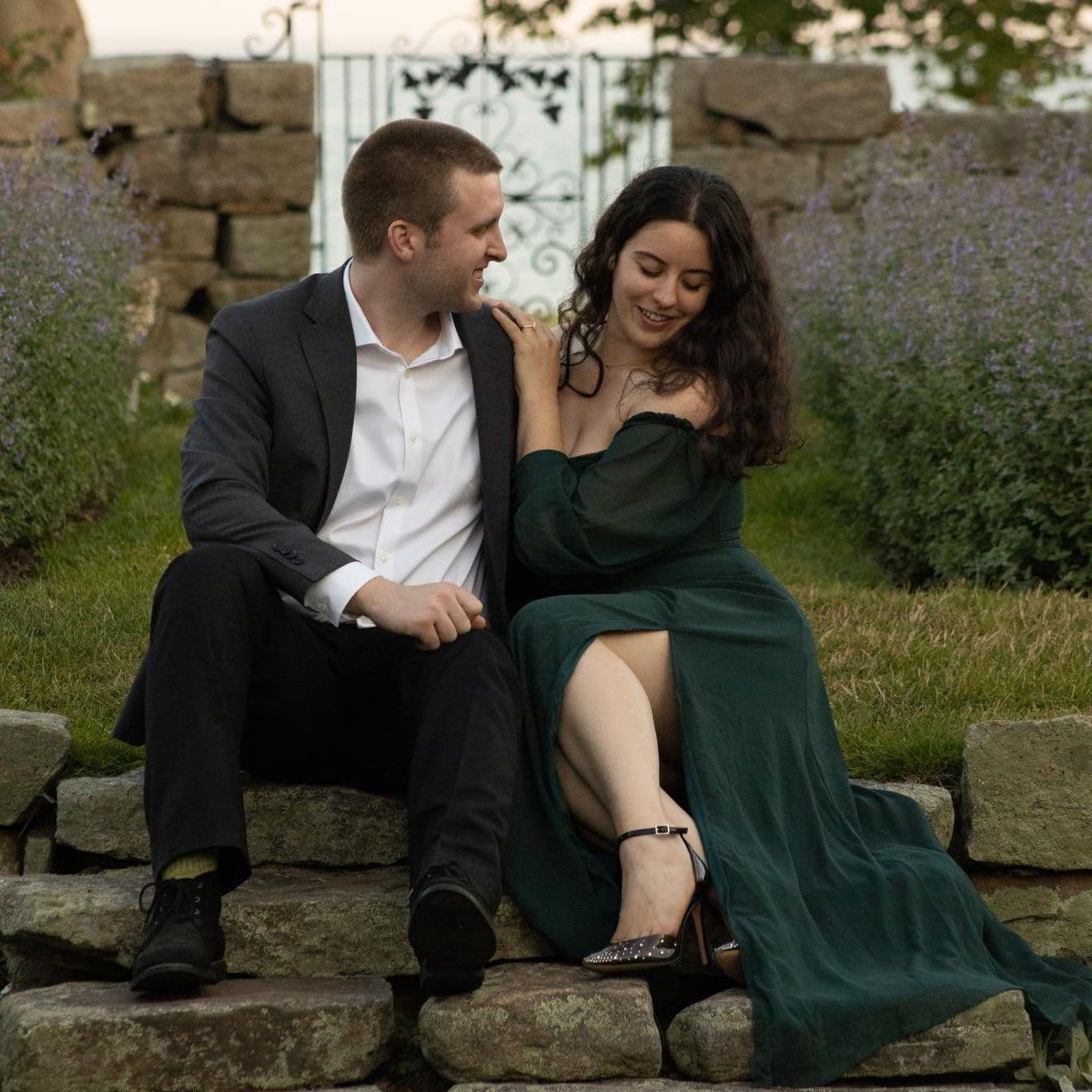 A well-dressed couple sitting on stone stairs in a garden.